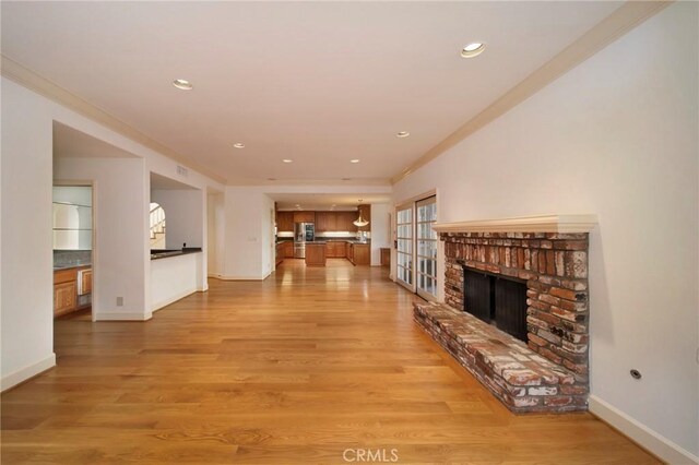 unfurnished living room with a brick fireplace, crown molding, and light wood-type flooring