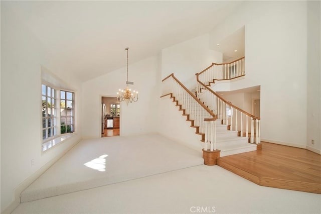 interior space with baseboards, a chandelier, stairs, wood finished floors, and high vaulted ceiling