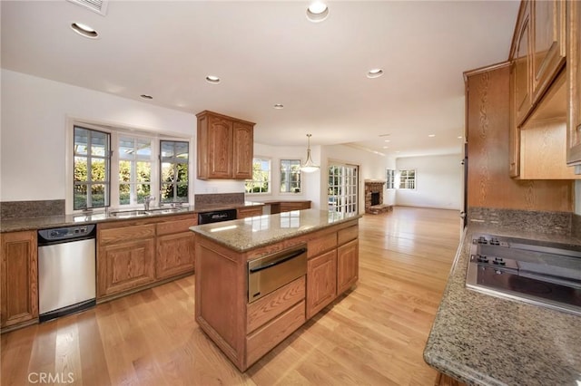 kitchen with a warming drawer, light wood-style floors, black appliances, and a center island