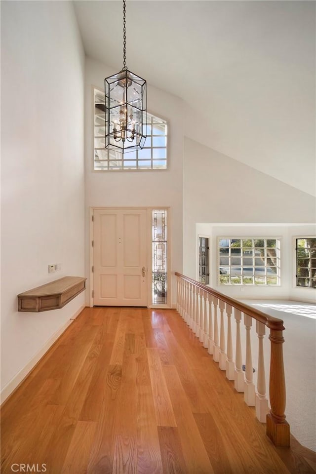 foyer with a towering ceiling, an inviting chandelier, and light hardwood / wood-style floors