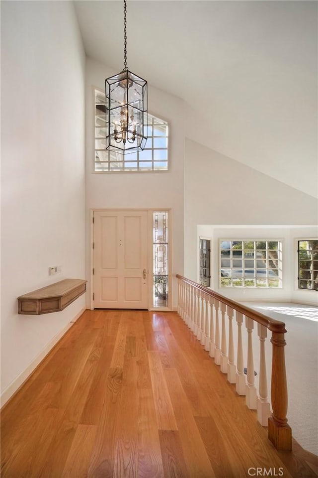 foyer entrance featuring an inviting chandelier, light wood-style floors, and high vaulted ceiling