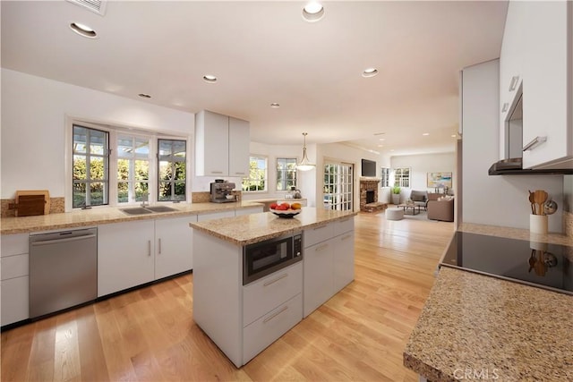 kitchen featuring light wood finished floors, black appliances, a kitchen island, recessed lighting, and white cabinetry