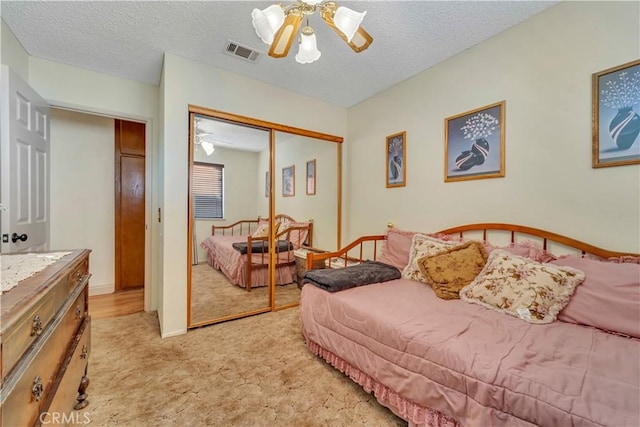 carpeted bedroom with ceiling fan, a textured ceiling, and a closet