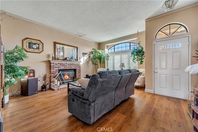 living room with a textured ceiling, ornamental molding, a fireplace, and hardwood / wood-style flooring