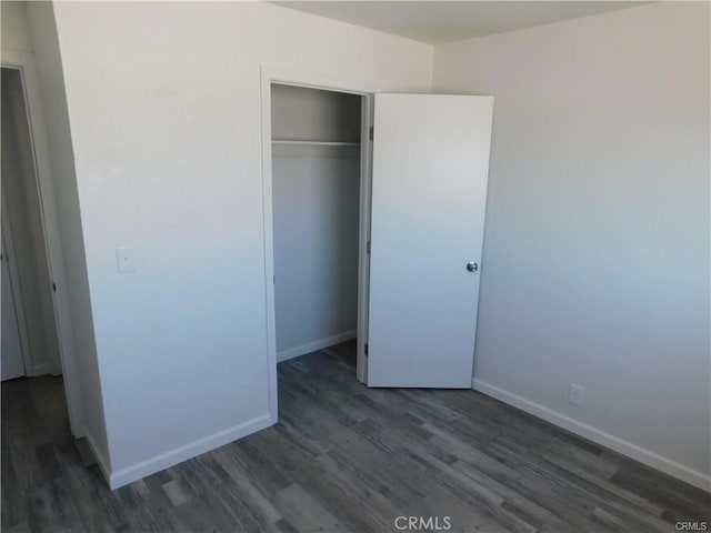 unfurnished bedroom featuring a closet and dark hardwood / wood-style floors