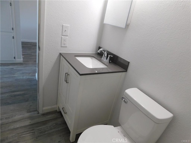 bathroom with toilet, vanity, and hardwood / wood-style floors