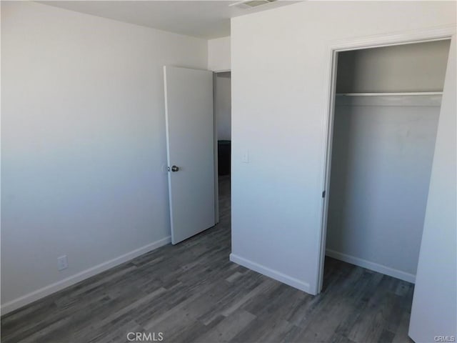 unfurnished bedroom featuring a closet and dark wood-type flooring