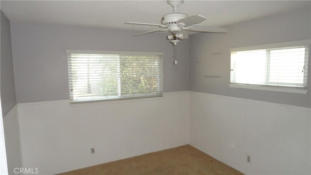 carpeted spare room featuring ceiling fan and a wealth of natural light