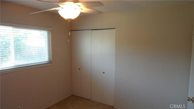 unfurnished bedroom with ceiling fan, multiple windows, and a closet