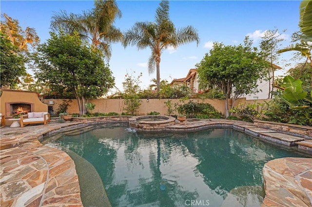 view of swimming pool with exterior fireplace, an in ground hot tub, and a patio