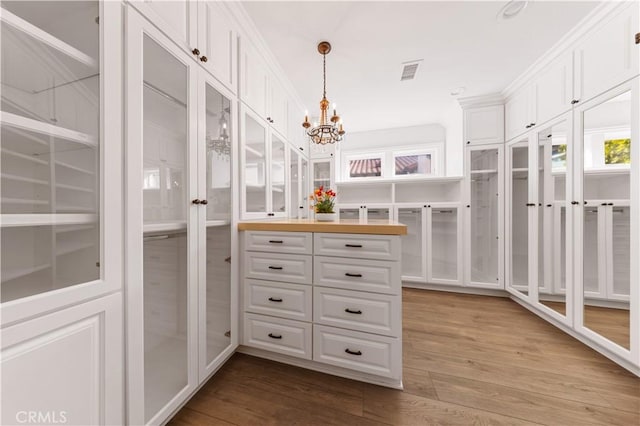 spacious closet with a chandelier and light hardwood / wood-style flooring