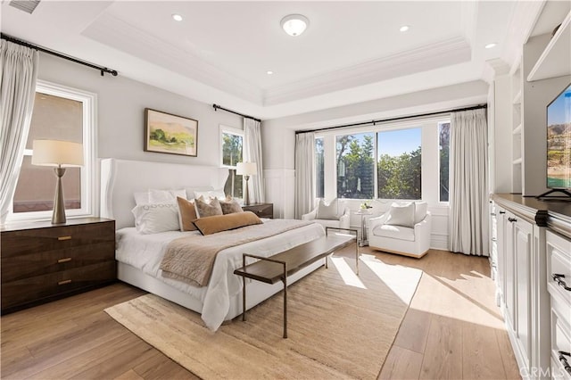 bedroom featuring a raised ceiling, light wood-type flooring, and ornamental molding