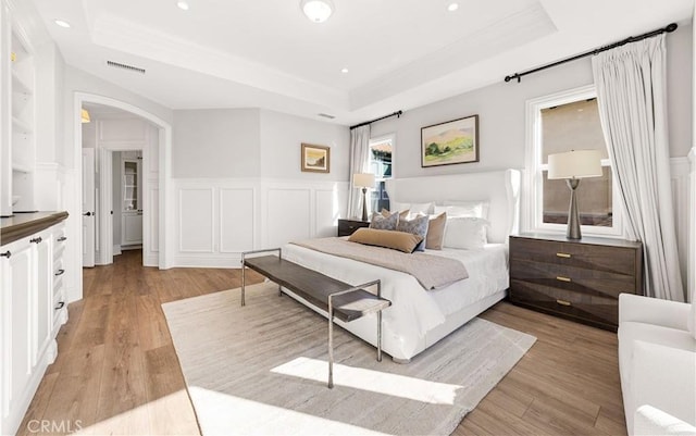 bedroom featuring a raised ceiling and light hardwood / wood-style floors