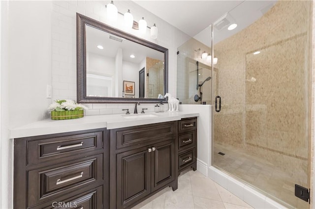 bathroom with a shower with shower door, vanity, and tile patterned floors