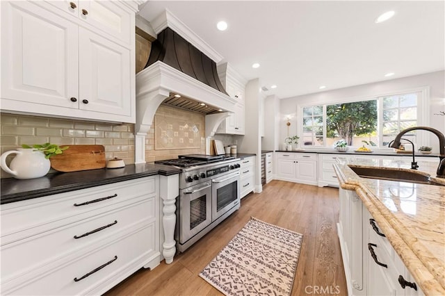 kitchen featuring white cabinets, decorative backsplash, sink, and range with two ovens