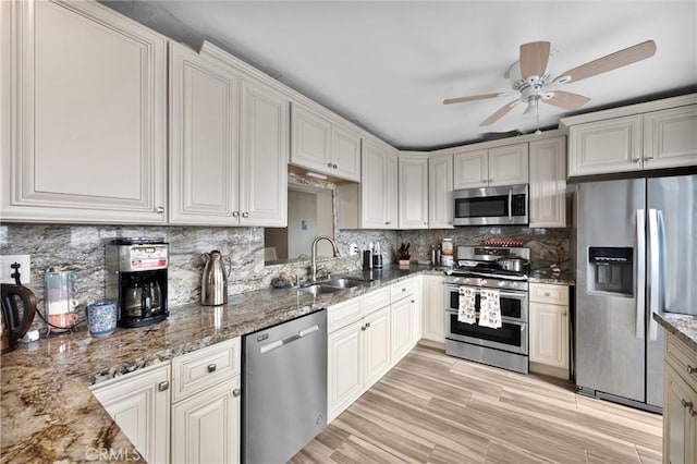 kitchen featuring stone counters, appliances with stainless steel finishes, tasteful backsplash, and sink