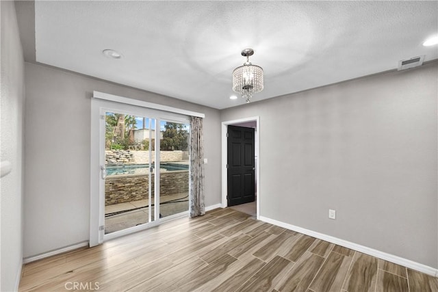 unfurnished room featuring a notable chandelier and a textured ceiling