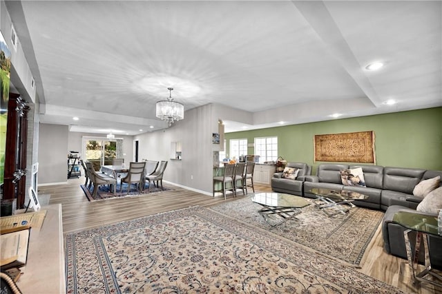 living room with a notable chandelier, a wealth of natural light, and hardwood / wood-style flooring