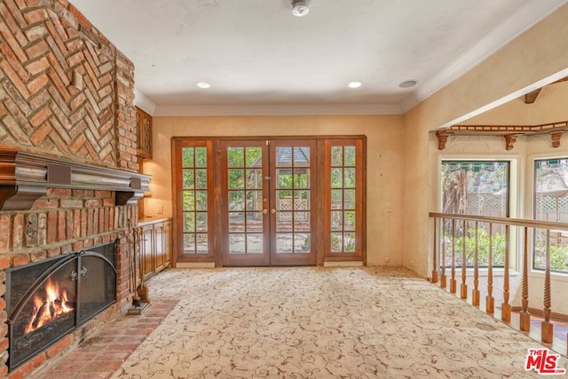 doorway to outside with light carpet, ornamental molding, a fireplace, and french doors