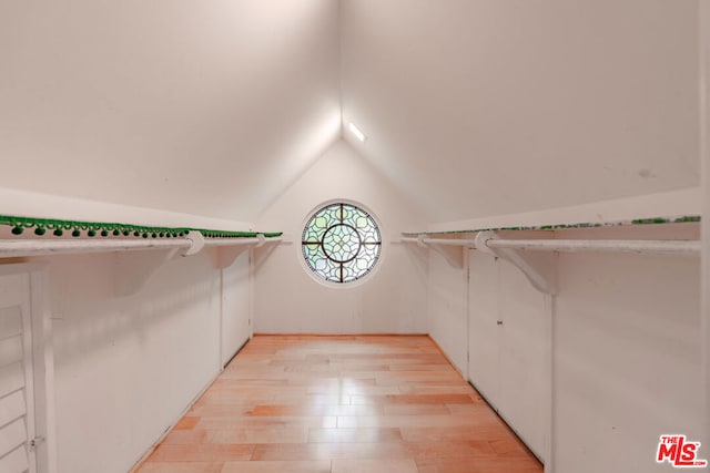 spacious closet with light hardwood / wood-style flooring and lofted ceiling