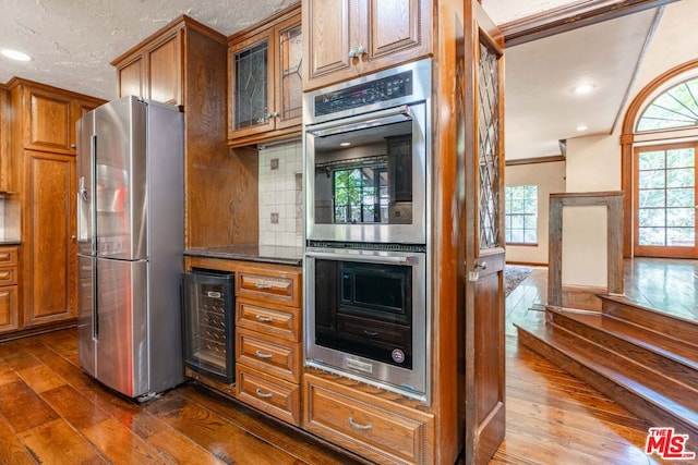 kitchen with stainless steel appliances, beverage cooler, dark hardwood / wood-style floors, and backsplash