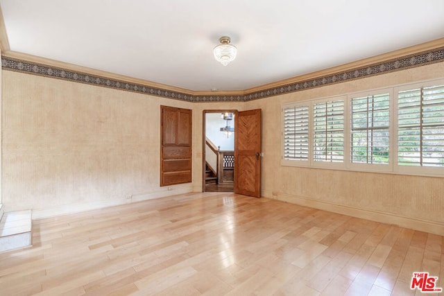 empty room featuring hardwood / wood-style flooring and ornamental molding