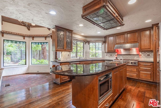 kitchen with appliances with stainless steel finishes, a kitchen breakfast bar, dark hardwood / wood-style flooring, a kitchen island, and sink