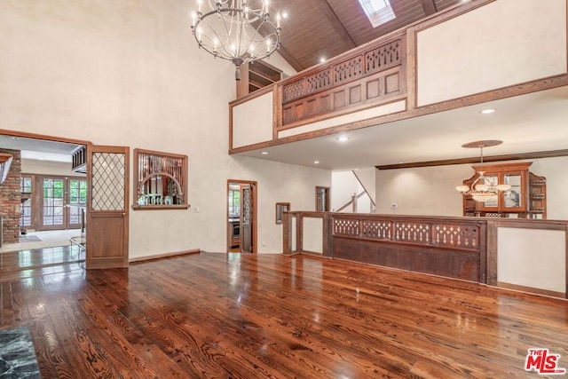 unfurnished living room featuring wood-type flooring, a towering ceiling, beamed ceiling, wood ceiling, and a chandelier