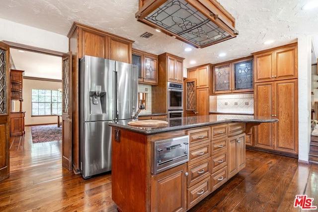 kitchen with tasteful backsplash, dark hardwood / wood-style floors, appliances with stainless steel finishes, and a kitchen island