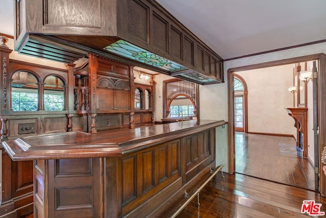 bar with dark hardwood / wood-style flooring, crown molding, dark brown cabinets, and sink