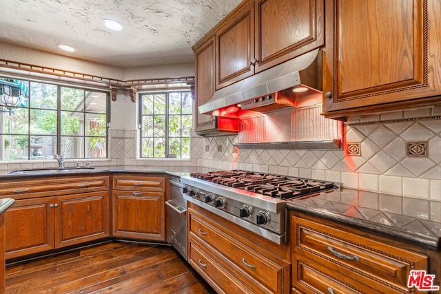 kitchen with dark wood-type flooring, sink, stainless steel gas stovetop, and tasteful backsplash