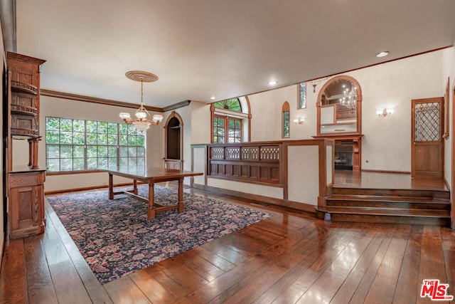 dining area with dark wood-type flooring, ornamental molding, and a notable chandelier