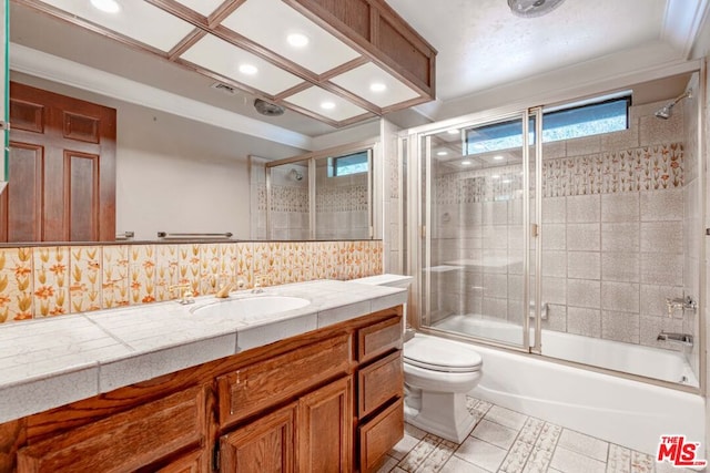 full bathroom with tasteful backsplash, bath / shower combo with glass door, vanity, toilet, and tile patterned floors