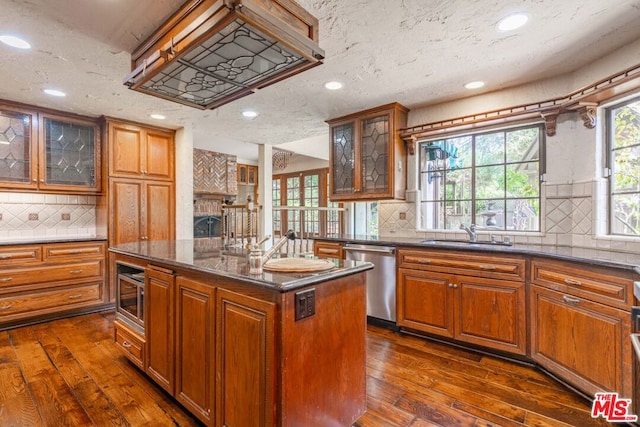 kitchen with stainless steel appliances, sink, dark hardwood / wood-style flooring, and a kitchen island with sink