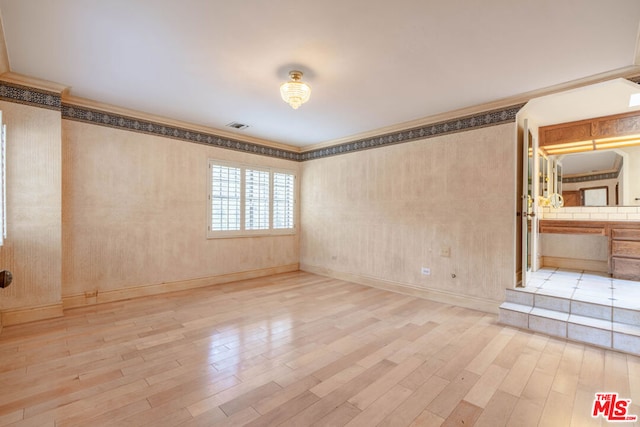 unfurnished room featuring light hardwood / wood-style floors and crown molding