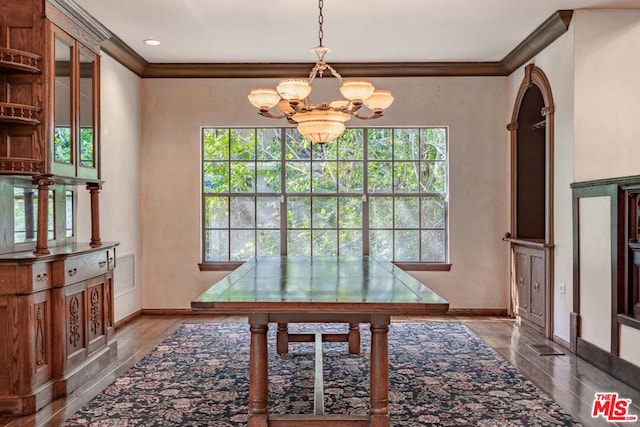 dining area featuring an inviting chandelier, ornamental molding, a healthy amount of sunlight, and wood-type flooring