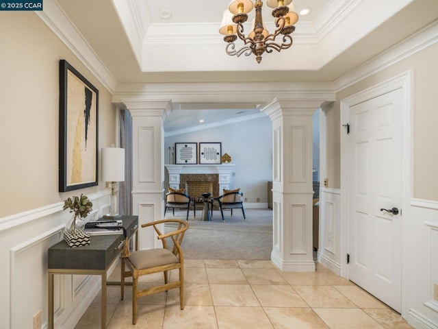 corridor featuring ornamental molding, a raised ceiling, and decorative columns