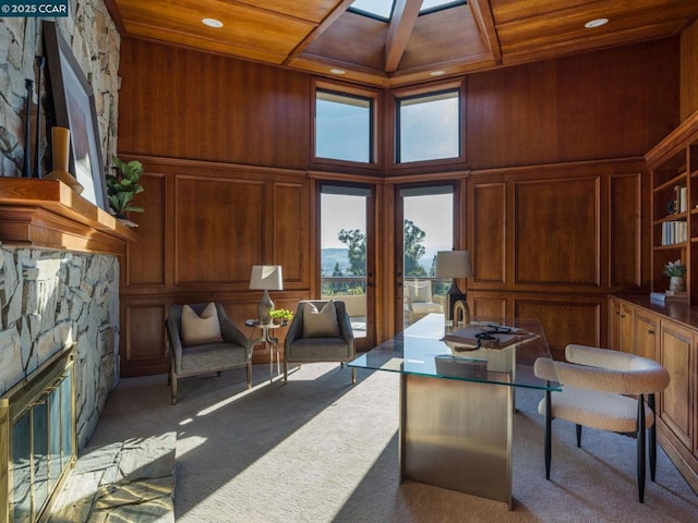 living area featuring a stone fireplace, a wealth of natural light, carpet floors, and wooden ceiling