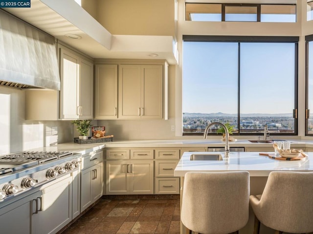 kitchen featuring sink, stainless steel gas cooktop, a kitchen breakfast bar, a mountain view, and wall chimney range hood