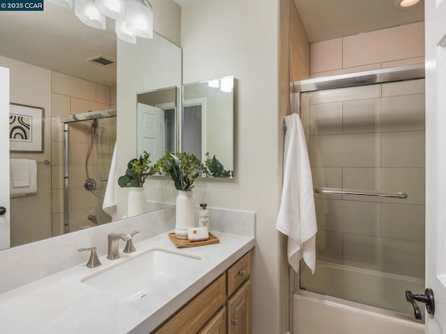 bathroom with vanity, shower / bath combination with glass door, and a textured ceiling