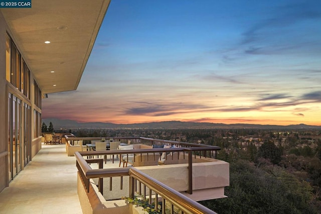 balcony at dusk featuring a mountain view