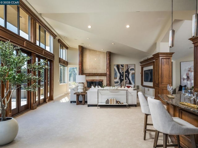 interior space featuring light carpet, high vaulted ceiling, a large fireplace, and a healthy amount of sunlight