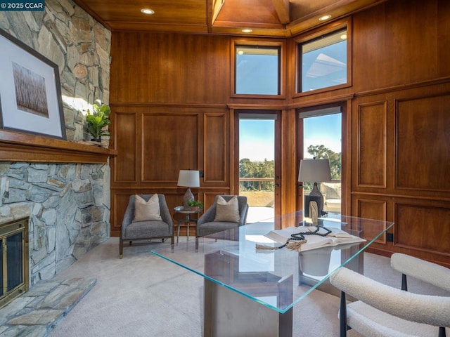 carpeted dining room with wood ceiling, a stone fireplace, wood walls, and a towering ceiling