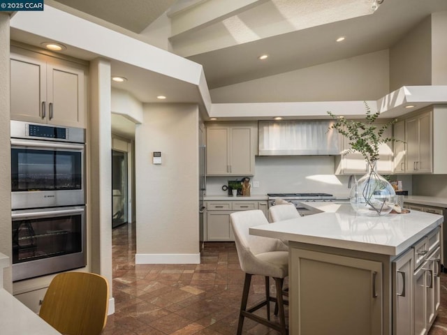 kitchen with vaulted ceiling, ventilation hood, a kitchen breakfast bar, a center island, and stainless steel double oven