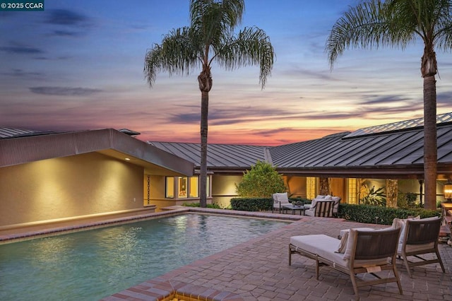 pool at dusk with a patio area