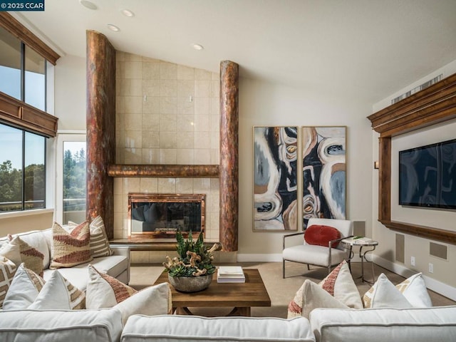 carpeted living room with a tiled fireplace and vaulted ceiling