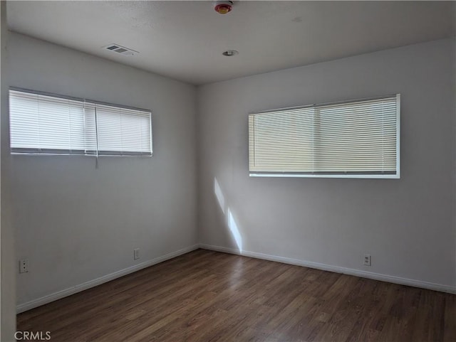 unfurnished room featuring dark wood-type flooring and plenty of natural light