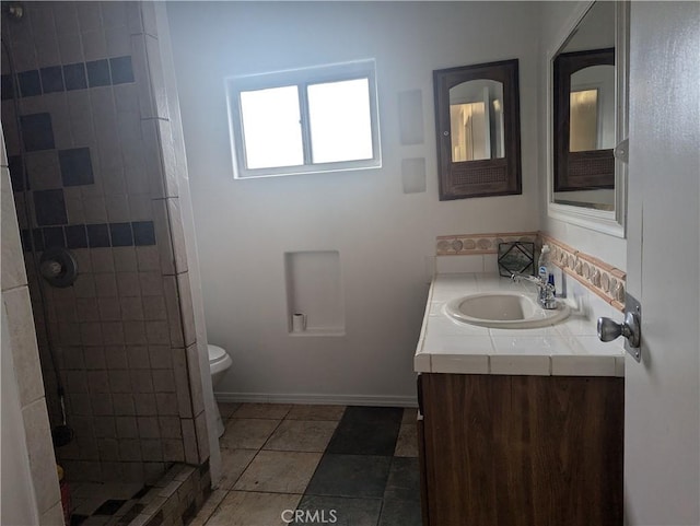 bathroom featuring toilet, tile patterned flooring, a tile shower, and vanity