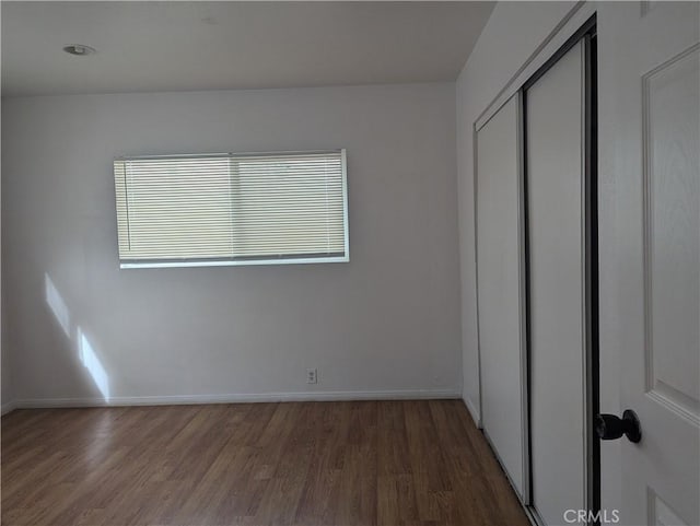 unfurnished bedroom with dark wood-type flooring and a closet