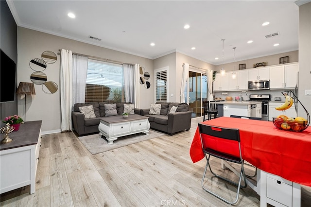 living room featuring sink, crown molding, and light hardwood / wood-style flooring